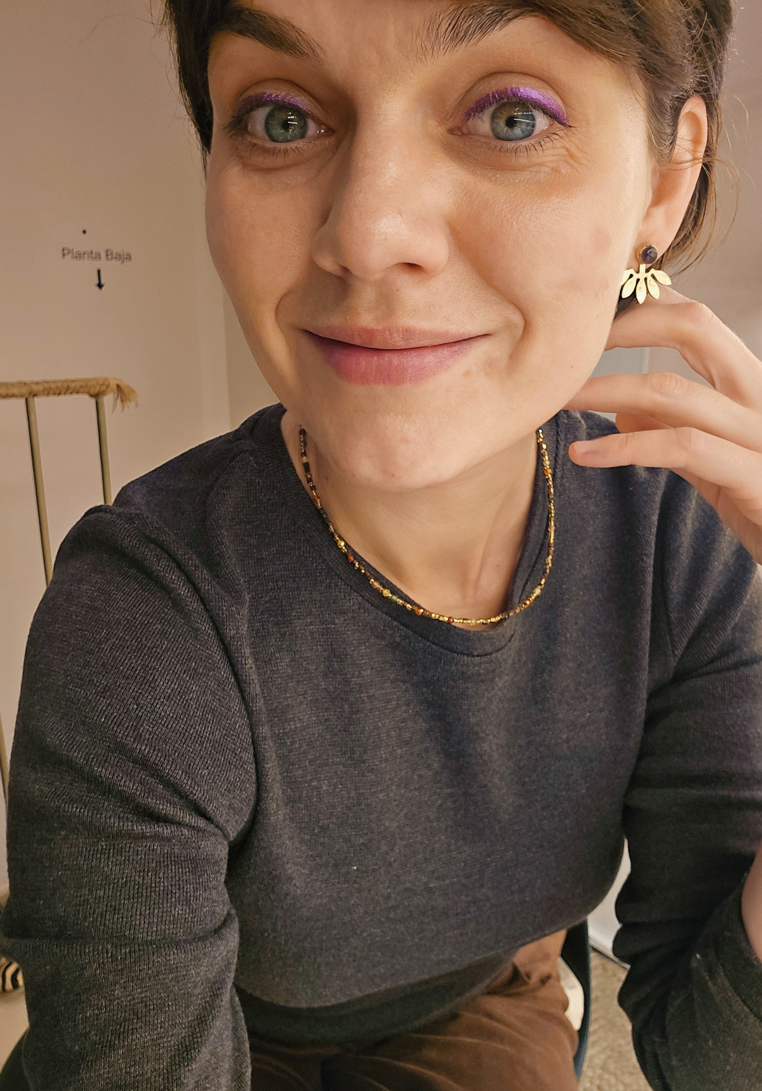 Woman wearing a brown sweater and  statement jewelry with a blurred background