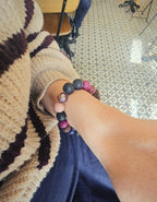 Hand wearing a multicolor beaded bracelet on a patterned floor in Madrid cafe
