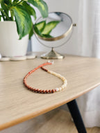 Tricolor necklace on a beige wooden coffee table with a plant and mirror from Leroy Merlin in the background