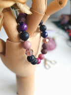 Bracelet with pink, violet beads on a wooden mannequin hand.